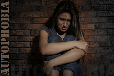 Image of Depressed young woman crying near brick wall. Autophobia - fear of isolation