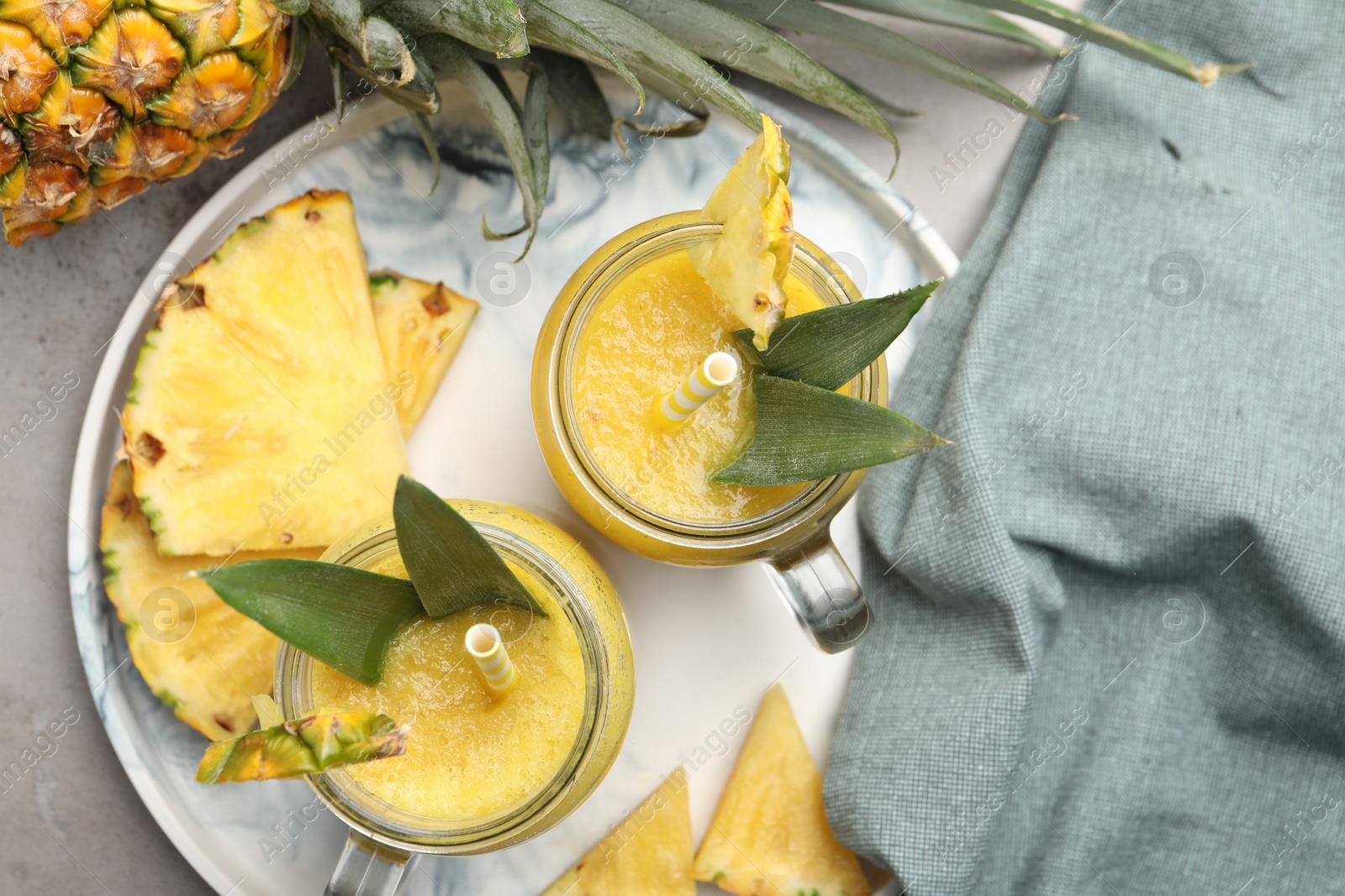 Tray with tasty pineapple smoothie and sliced fruit on grey table, flat lay Photo of Tray with tasty pineapple smoothie and sliced fruit on grey table, flat lay
