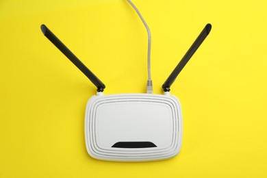 Photo of Modern Wi-Fi router on yellow background, top view