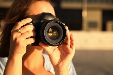 Young photographer taking picture with professional camera outdoors