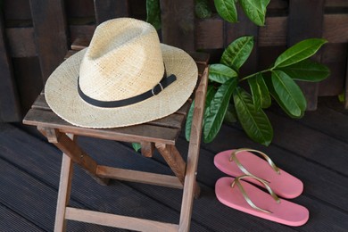 Photo of Stylish hat and flip flops near wooden fence. Beach accessories