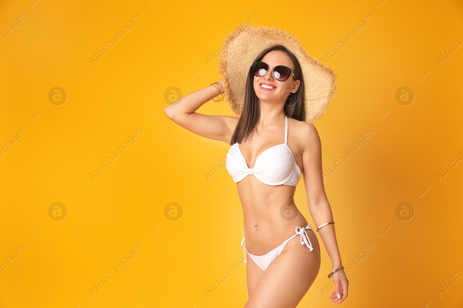 Photo of Pretty sexy woman with slim body in stylish  white bikini on orange background, space for text