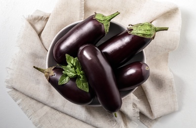 Photo of Ripe eggplants and basil on white table, top view