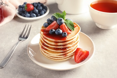 Photo of Plate with pancakes and berries on table