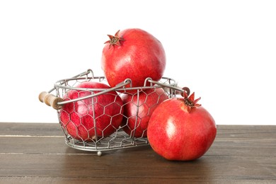 Photo of Fresh pomegranates in basket on wooden table against white background