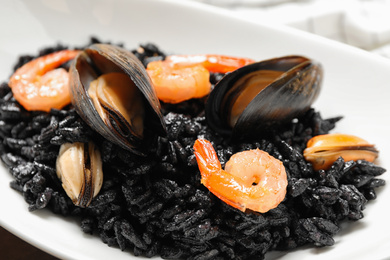 Delicious black risotto with seafood in plate, closeup