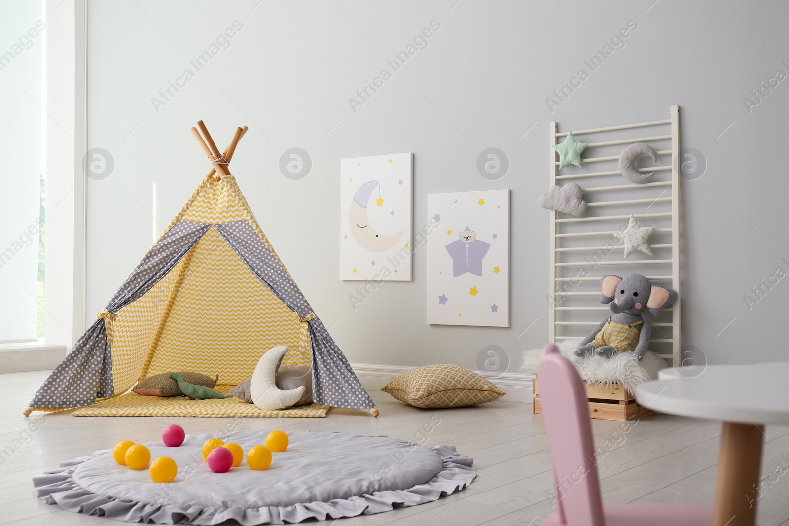 Photo of Stylish child's room interior with adorable paintings and play tent