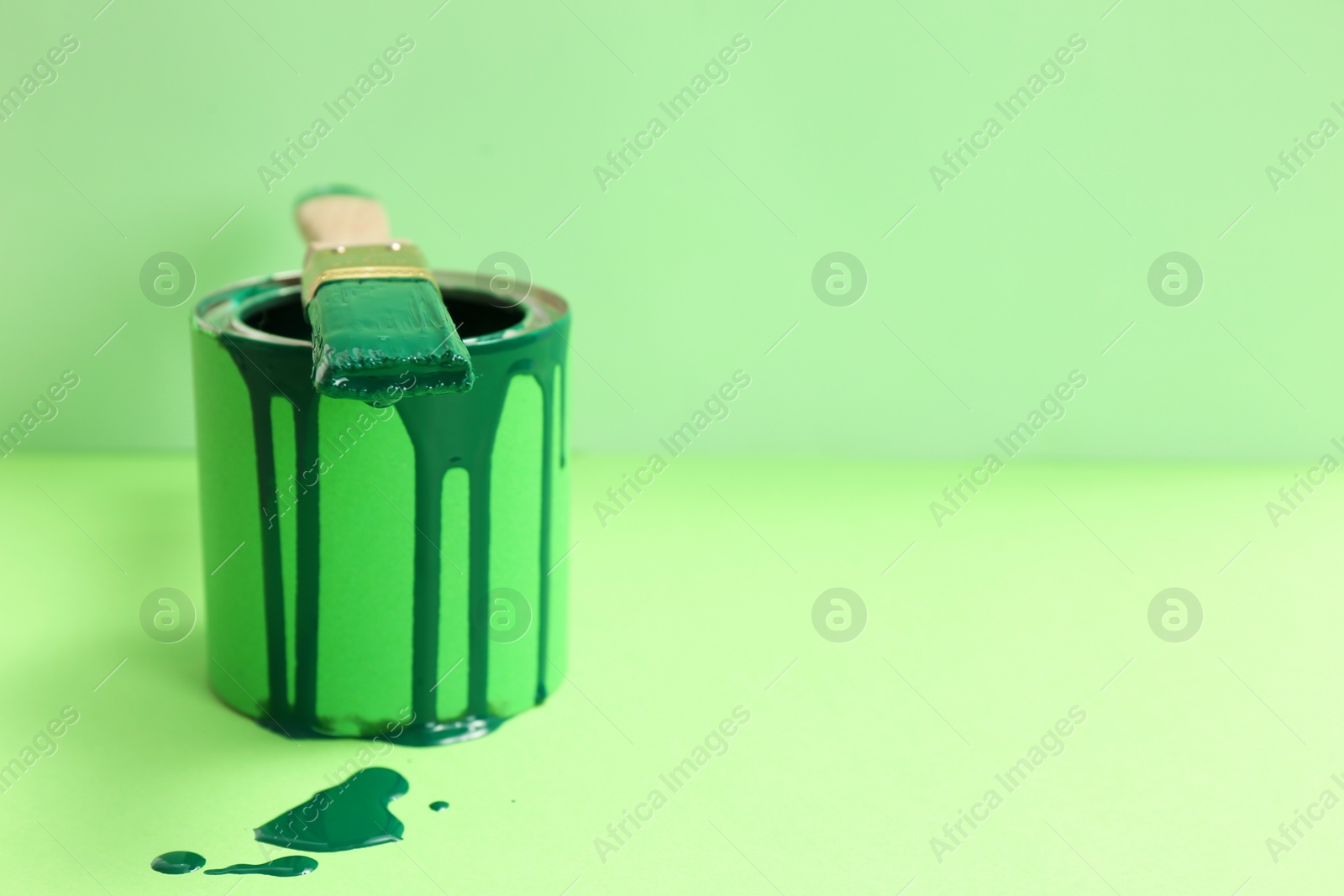 Photo of Can of green paint with brush on color background. Space for text