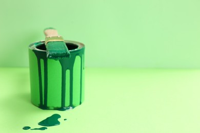 Can of green paint with brush on color background. Space for text