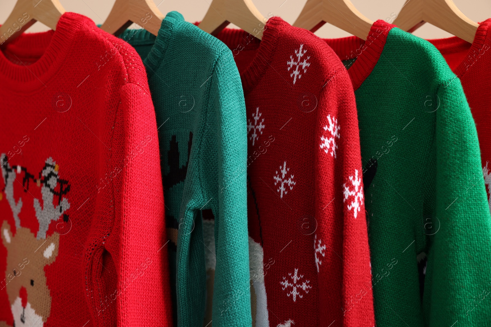 Photo of Different Christmas sweaters hanging on rack, closeup