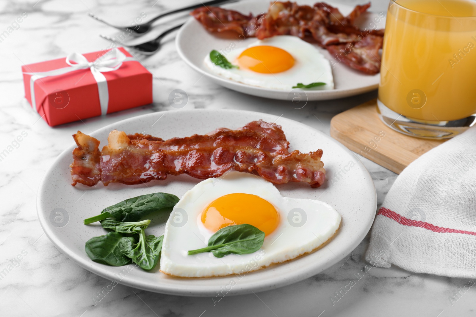 Photo of Romantic breakfast with fried bacon and heart shaped egg on white marble table. Valentine's day celebration