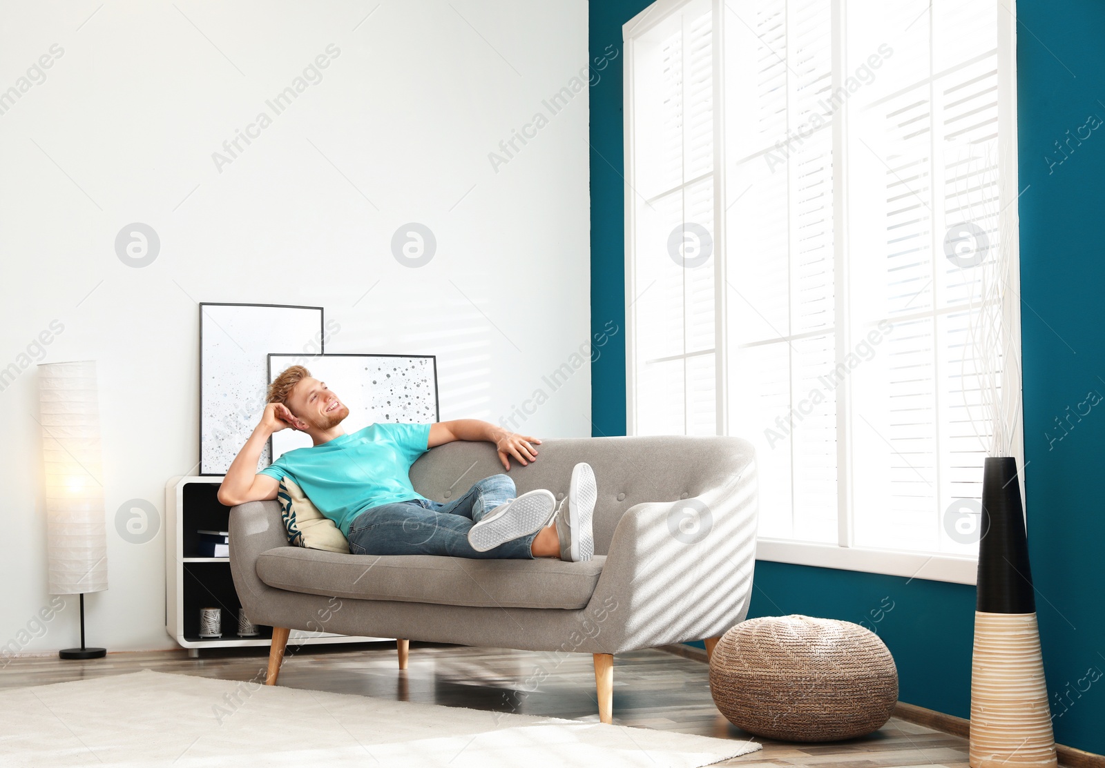 Photo of Happy young man resting on sofa under air conditioner at home