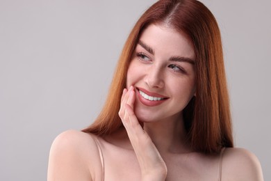 Portrait of smiling woman on grey background, closeup