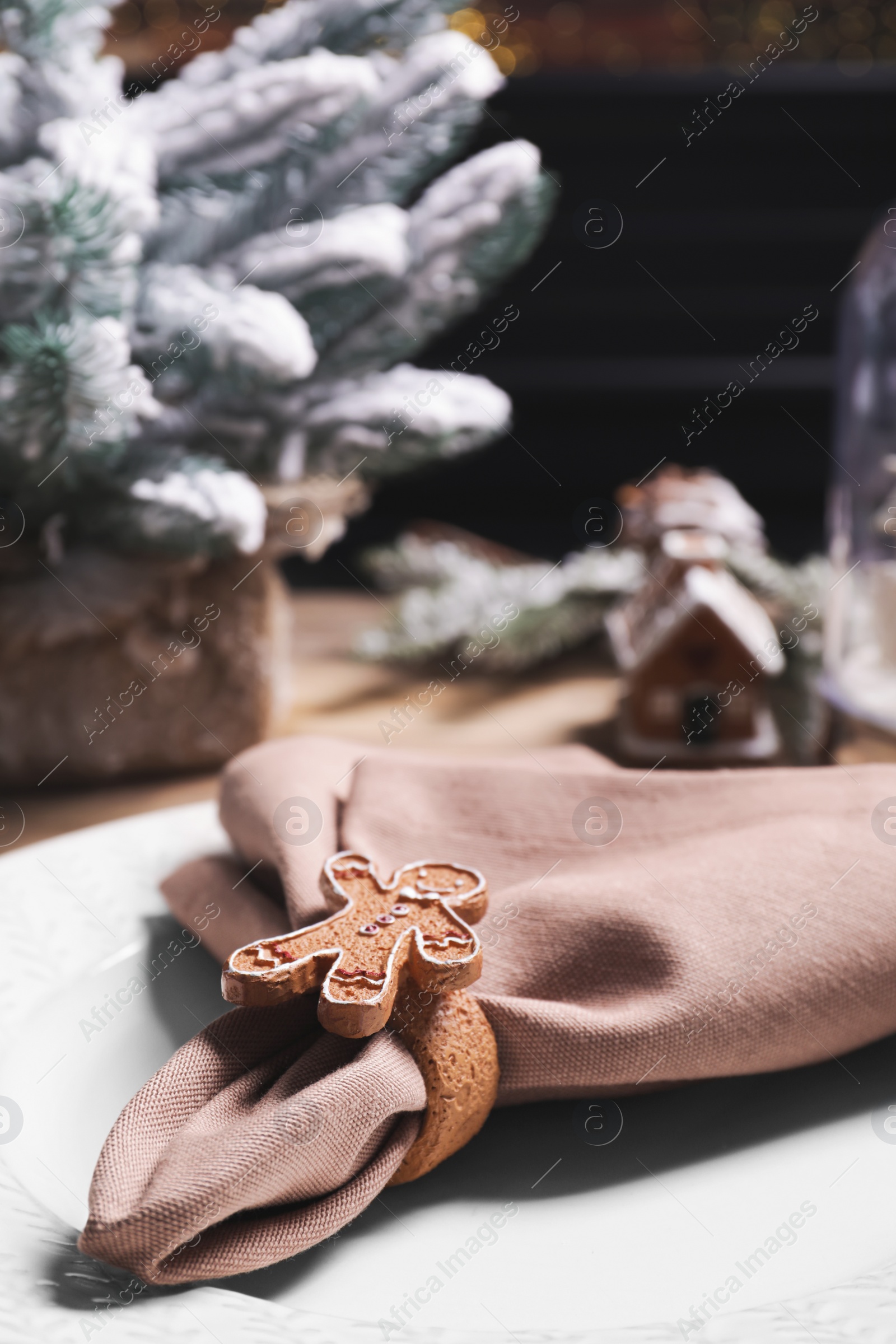 Photo of Plate and fabric napkin with decorative ring on wooden table, closeup