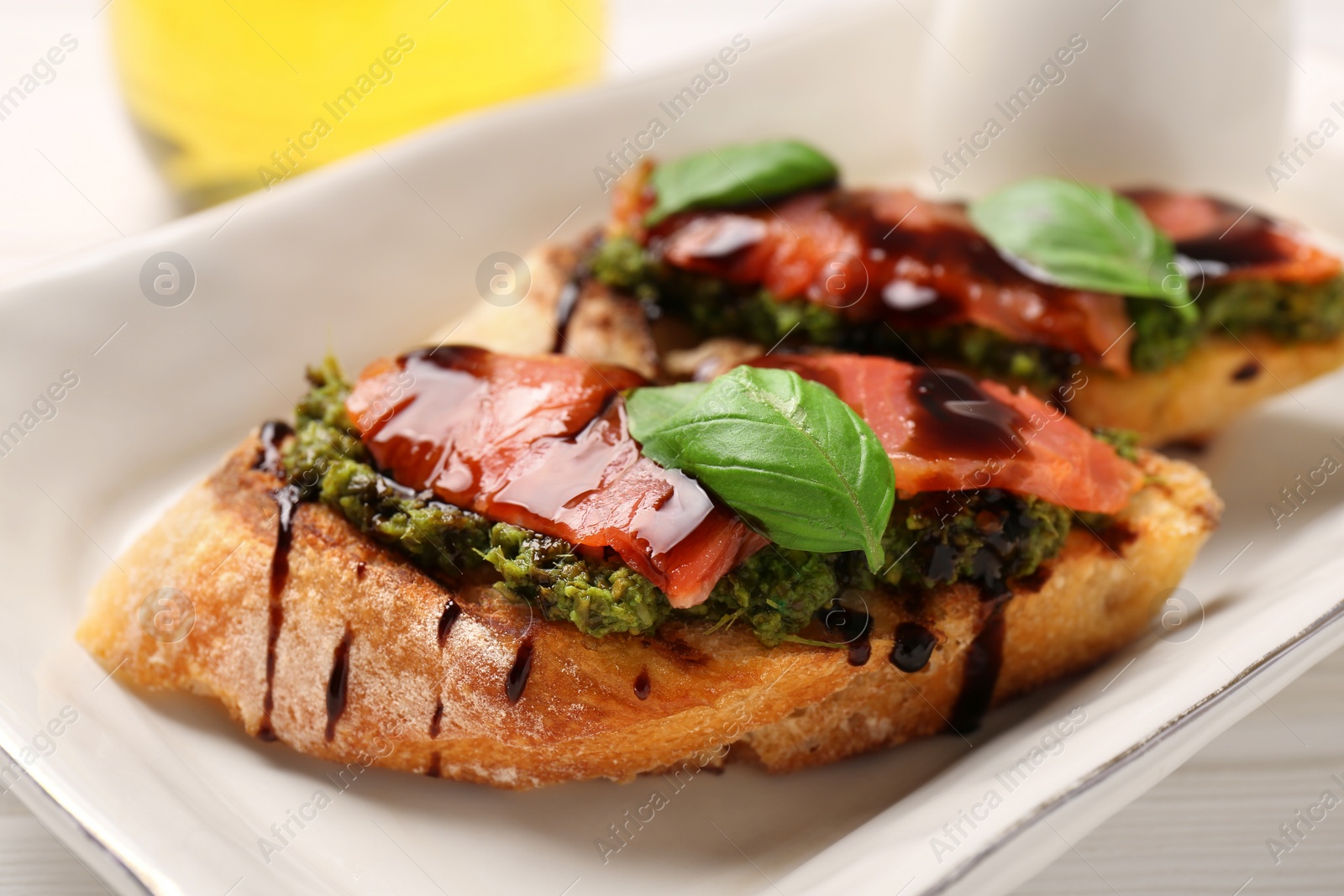 Photo of Delicious bruschettas with balsamic vinegar and toppings on white table, closeup
