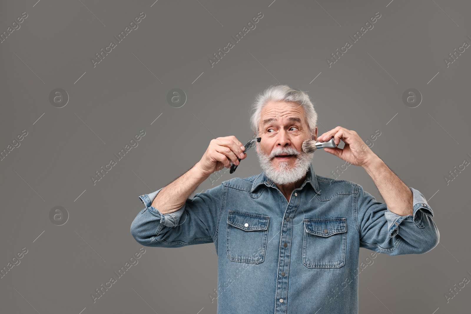 Photo of Senior man with mustache holding razor and brush on grey background, space for text