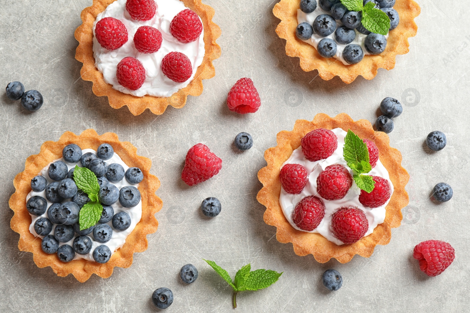 Photo of Delicious sweet pastries with berries on grey table, flat lay