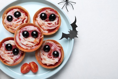 Photo of Cute monster tartlets served on white table, flat lay with space for text. Halloween party food