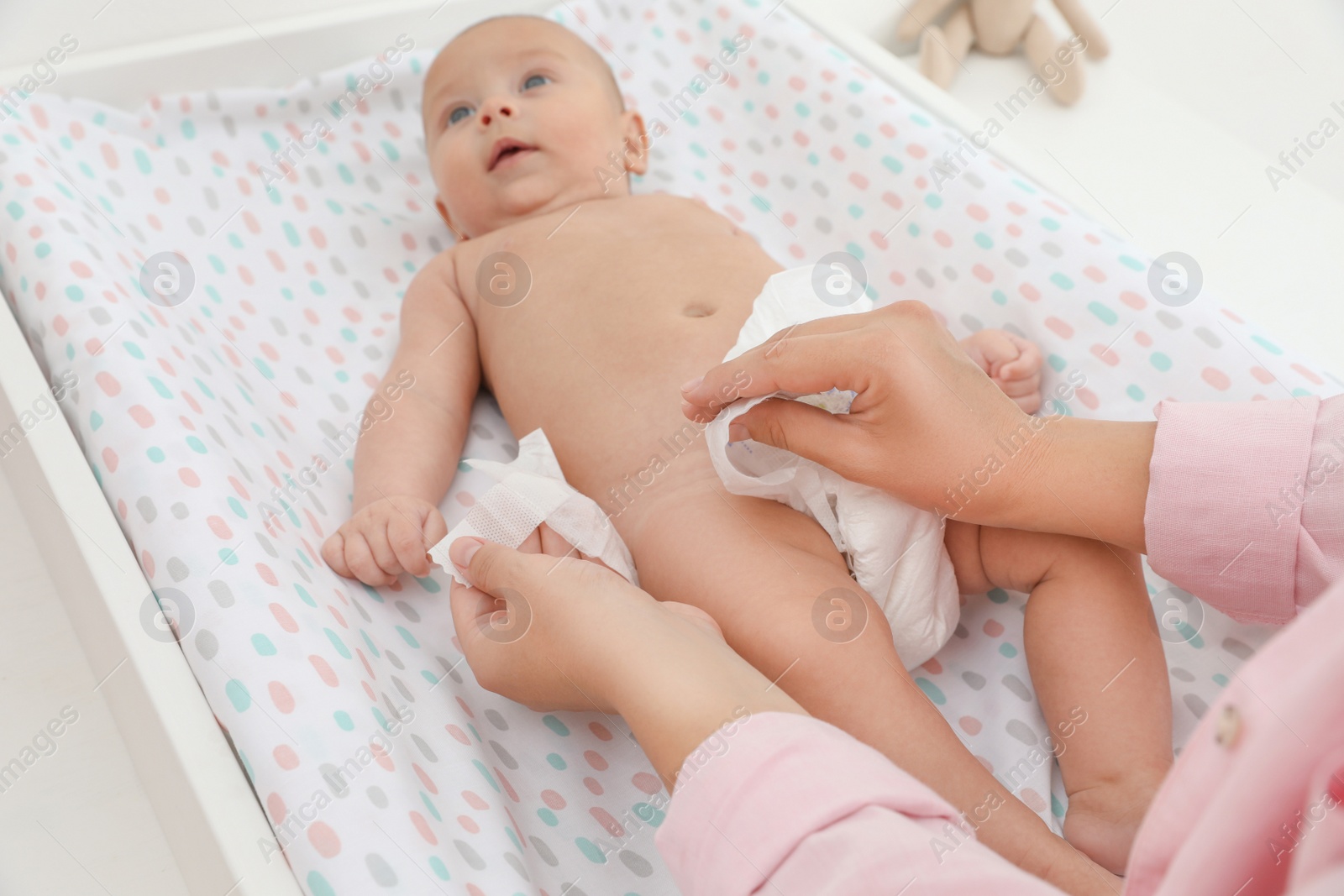 Photo of Mother changing her baby's diaper on table at home