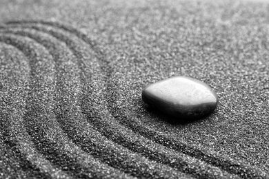 Photo of Zen garden stone on black sand with pattern, closeup