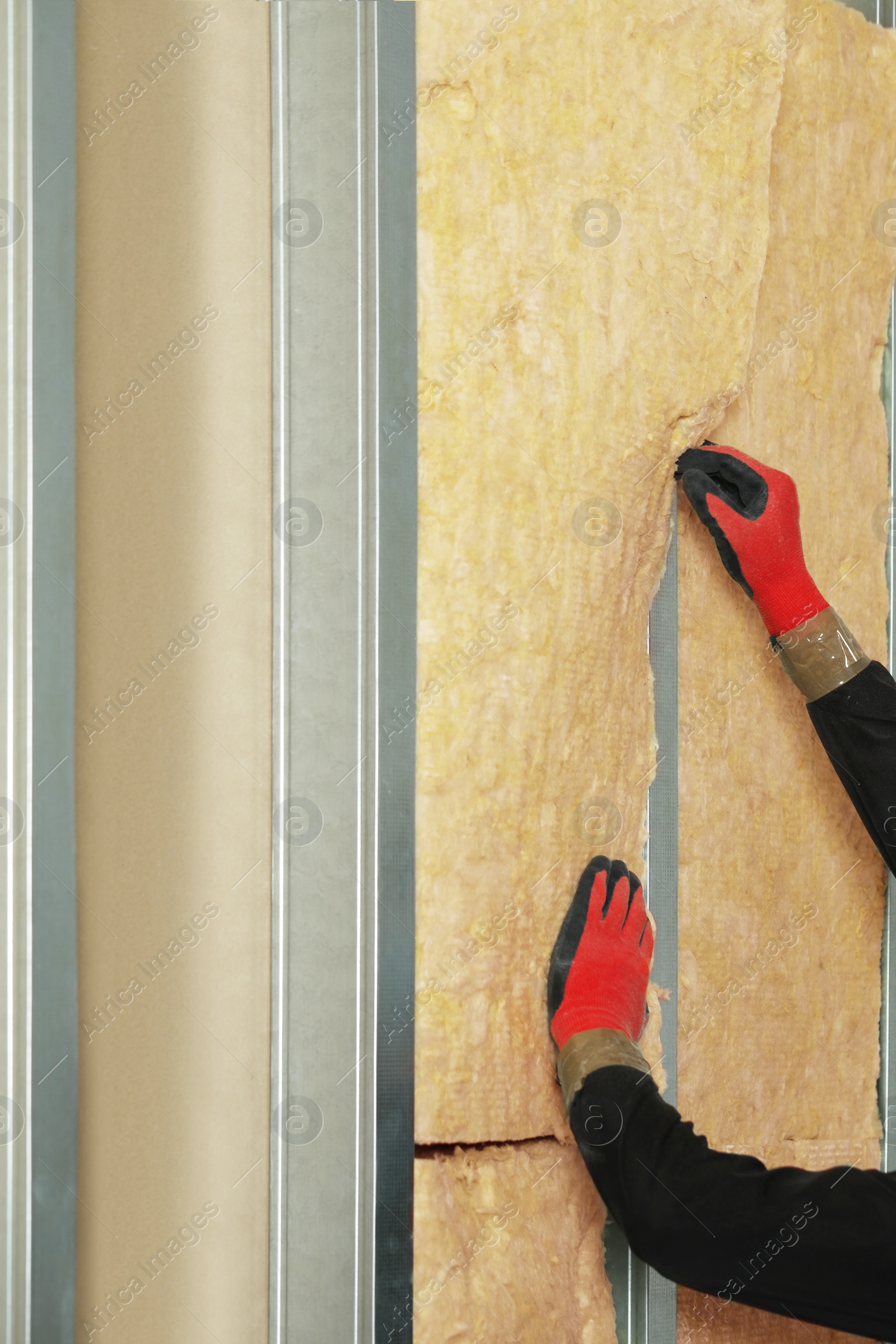 Photo of Worker installing thermal insulation material on wall, closeup