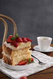 Piece of tasty cake with fresh strawberries, mint and cup of tea on wooden table