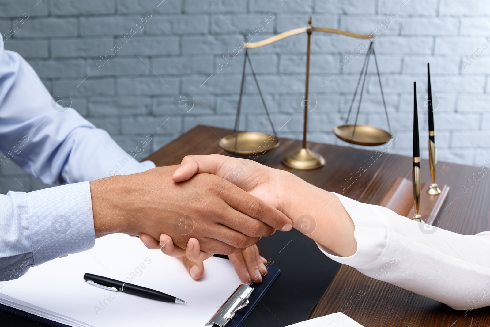 Photo of Male lawyer shaking hands with client at table, closeup