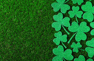 Photo of Flat lay composition with clover leaves on green grass, space for text. St. Patrick's Day celebration