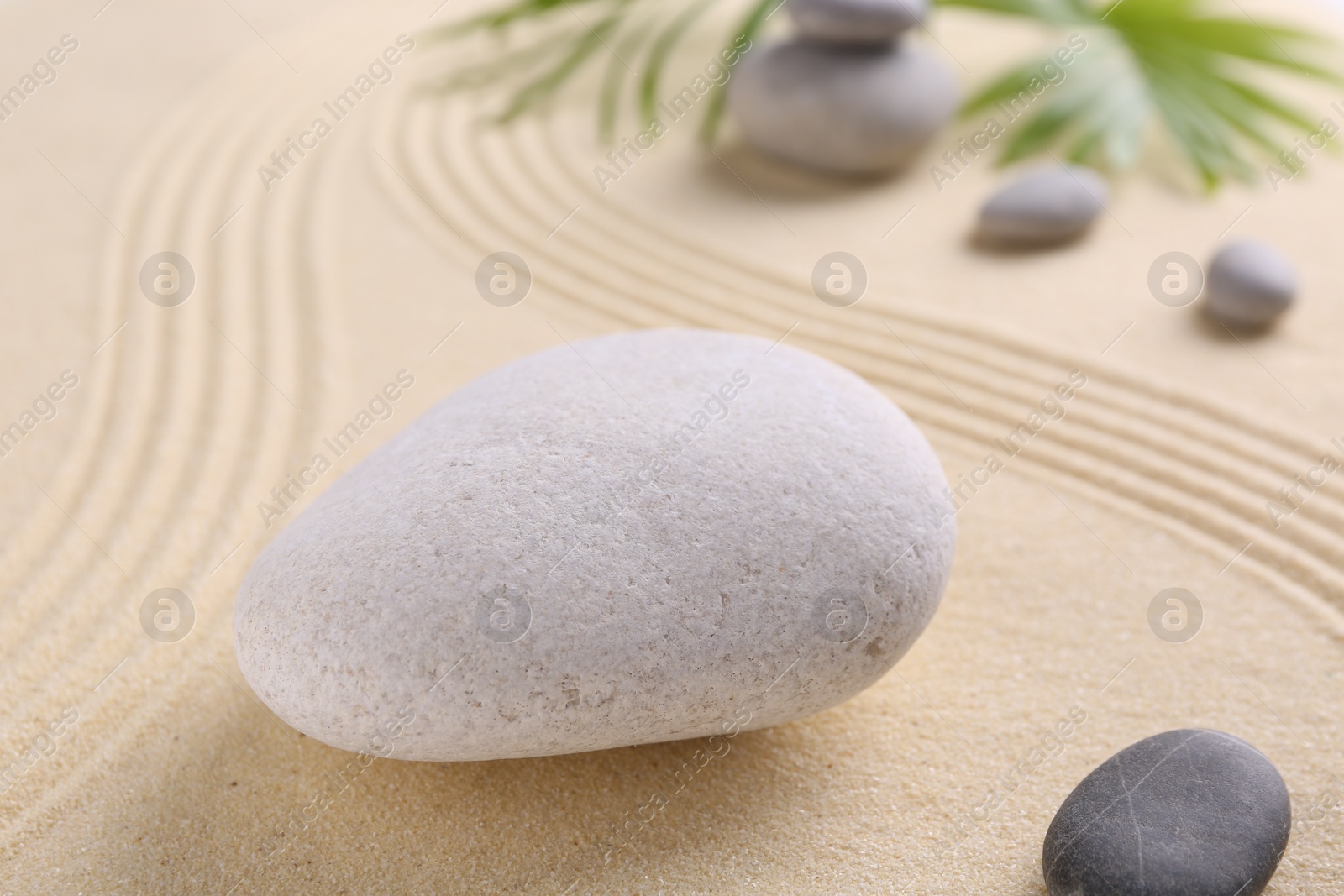 Photo of Zen garden stones on sand with pattern, closeup