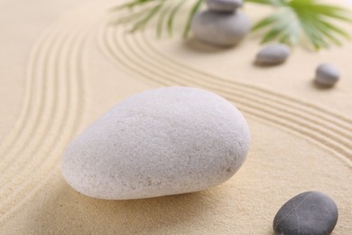 Photo of Zen garden stones on sand with pattern, closeup