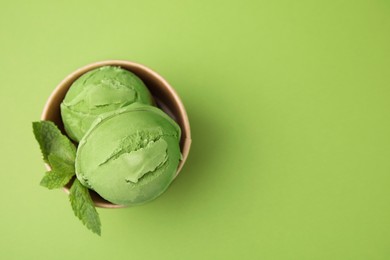 Photo of Paper cup with tasty matcha ice cream on light green background, top view. Space for text