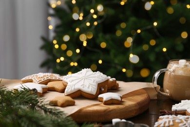 Photo of Decorated cookies on table against blurred Christmas lights, closeup