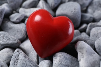 Photo of One red decorative heart on grey stones, closeup