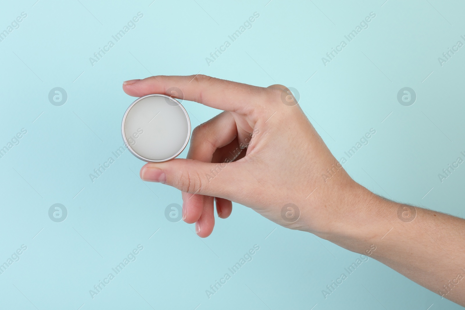 Photo of Woman with lip balm on light turquoise background, closeup