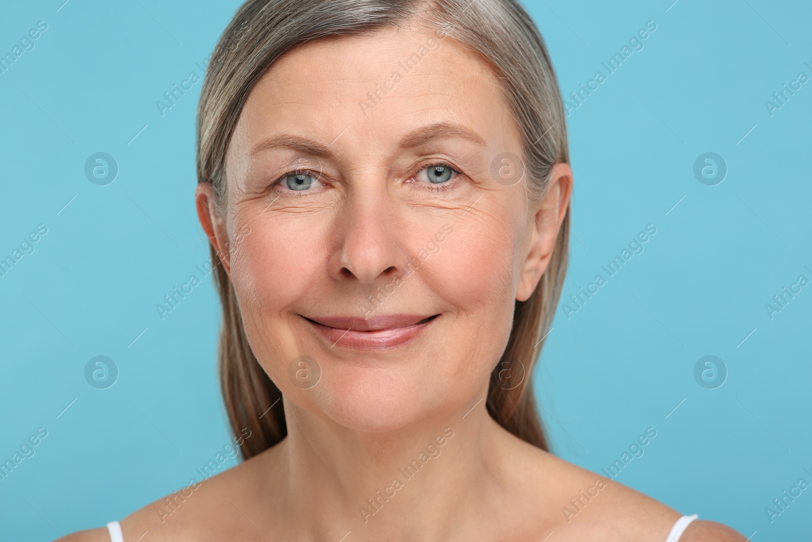 Photo of Portrait of senior woman with aging skin on light blue background. Rejuvenation treatment