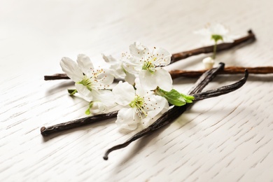 Vanilla sticks and flowers on wooden background