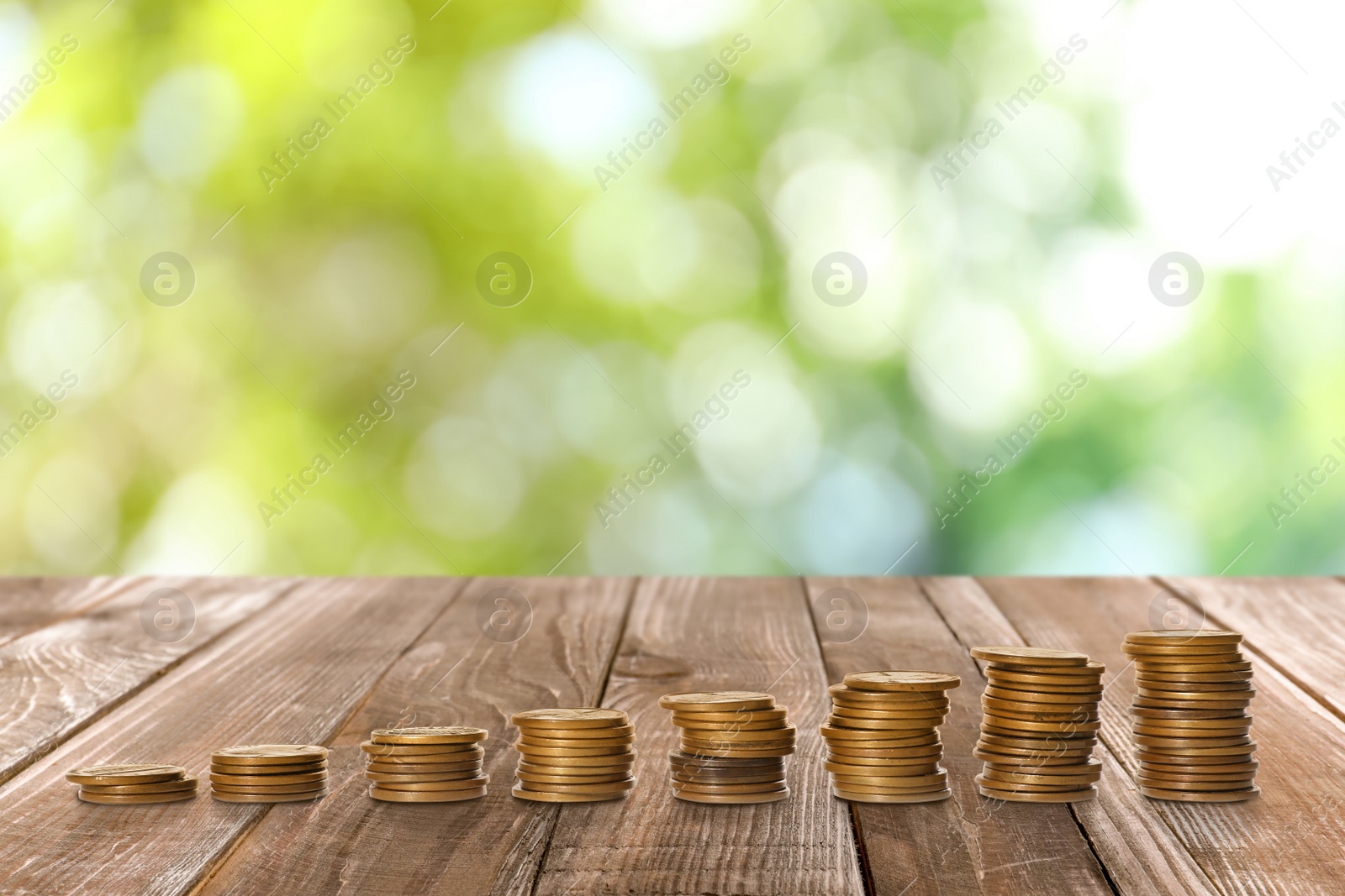 Image of Stacked coins on wooden table against blurred background. Investment concept