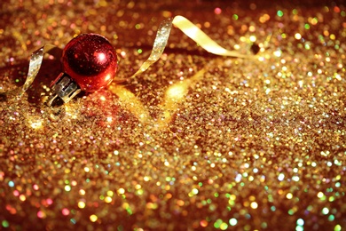 Golden glitter, Christmas ball and streamer on color background