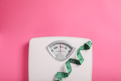 Photo of Weight loss concept. Scales and measuring tape on pink background, top view. Space for text