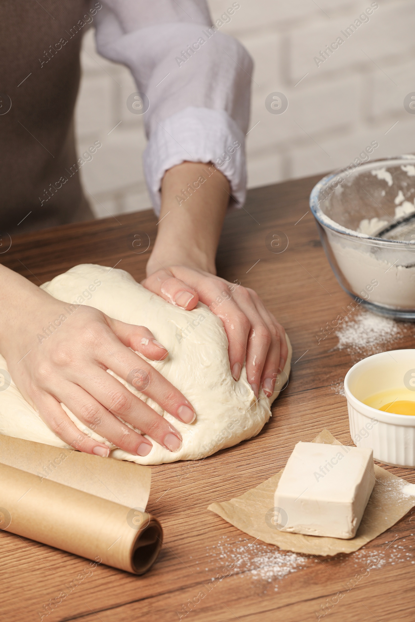 Photo of Woman kneading yeast dough for cake at wooden table, closeup