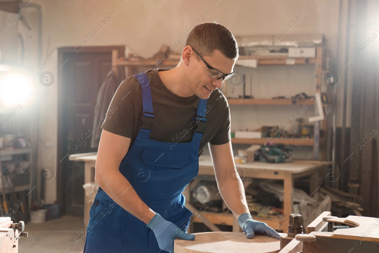 Photo of Professional carpenter grinding piece of wood in workshop