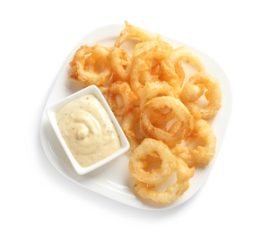 Photo of Plate with delicious crispy onion rings and sauce on white background, top view