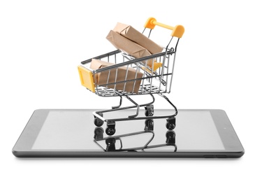 Internet shopping. Small cart with boxes and modern tablet on white background