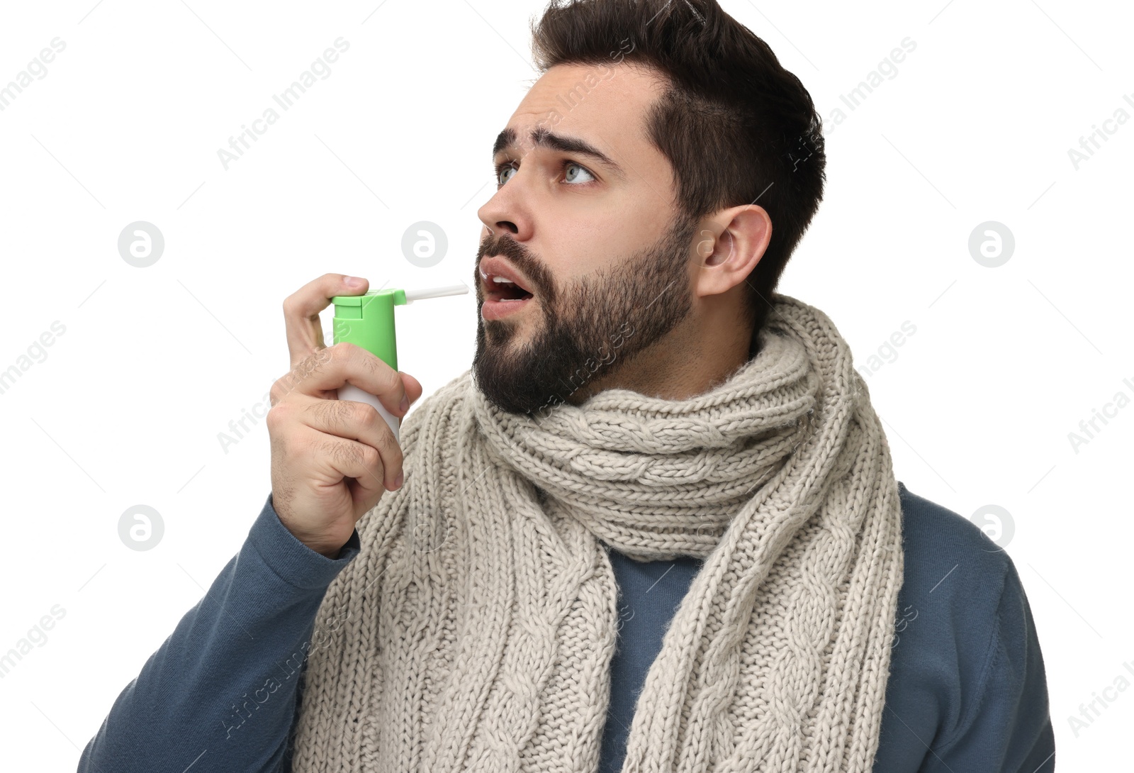 Photo of Young man with scarf using throat spray on white background