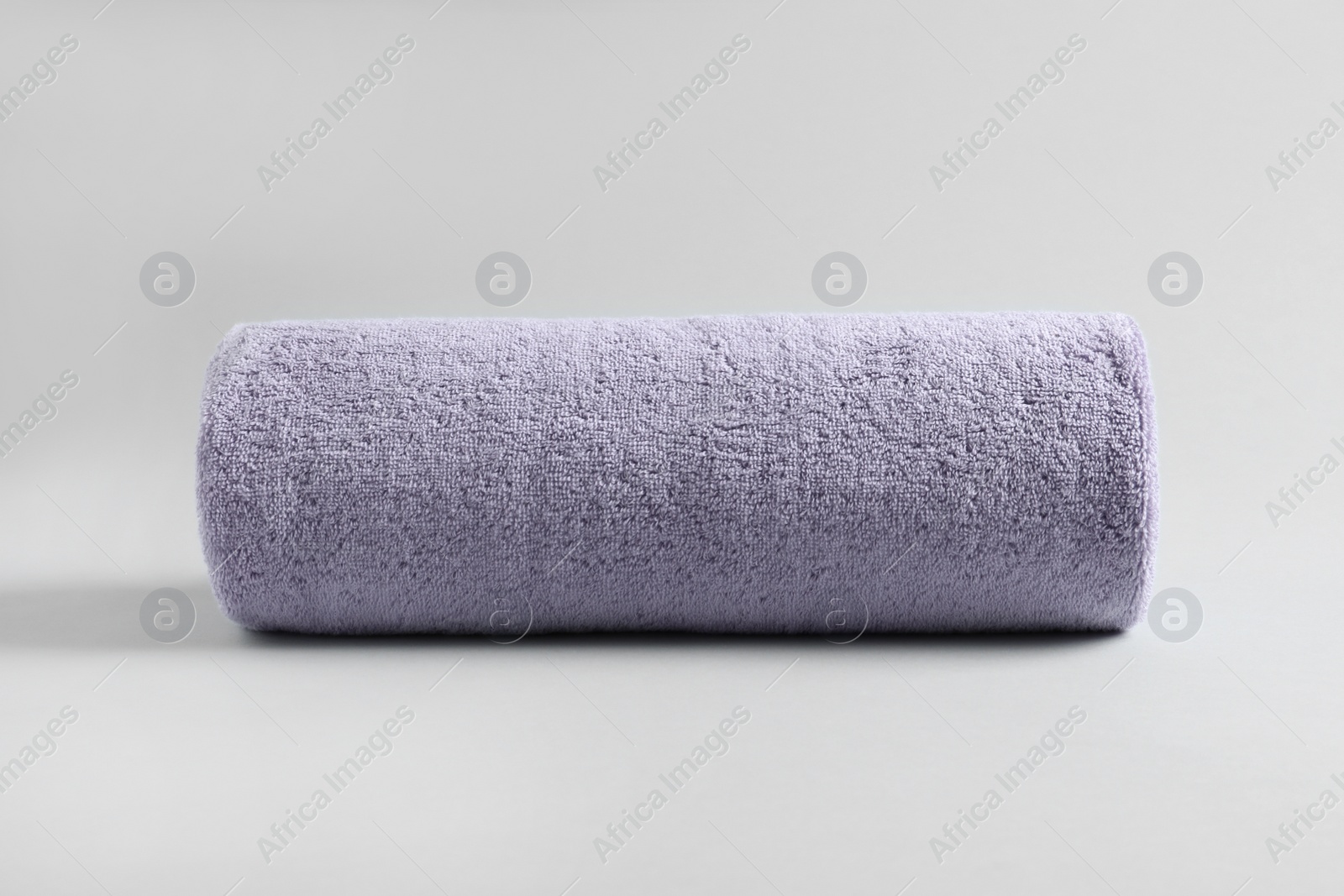 Photo of Fresh fluffy rolled towel on grey background