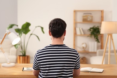 Photo of Home workplace. Man working at wooden desk in room, back view