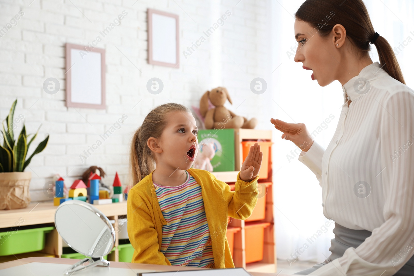 Photo of Speech therapist working with little girl in office