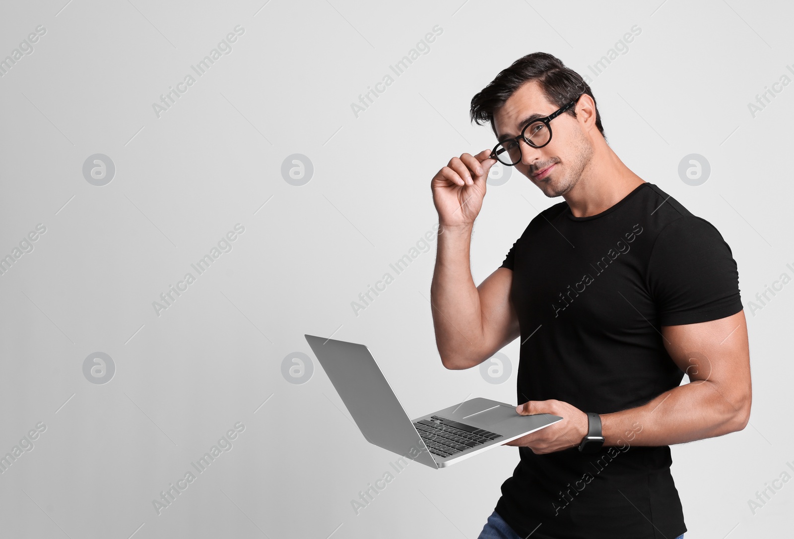 Photo of Handsome young man with laptop on grey background. Space for text