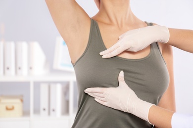 Photo of Doctor checking woman's breast at hospital, closeup. Space for text