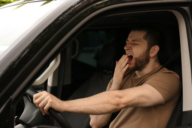 Photo of Tired man yawning while driving his modern car